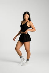 Three quarter angle, in movement, KYDRA Pleated Shorts in Black #color_Black
