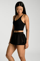 Close view of the pleated drape and hem, KYDRA Pleated Shorts in Black #color_Black